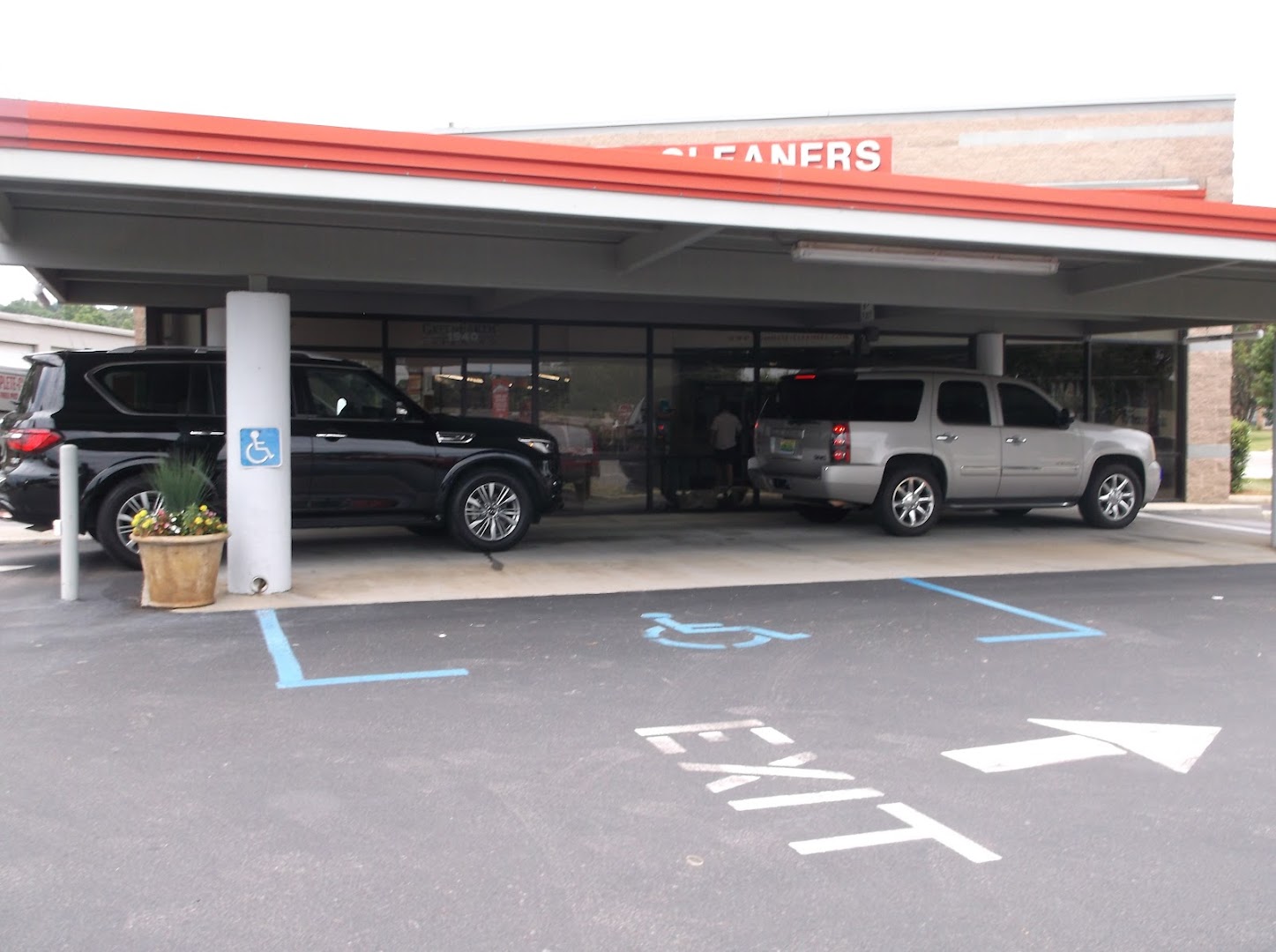 Two cars in the Tutwiler drive-thru lane during the day, EXIT arrow on pavement